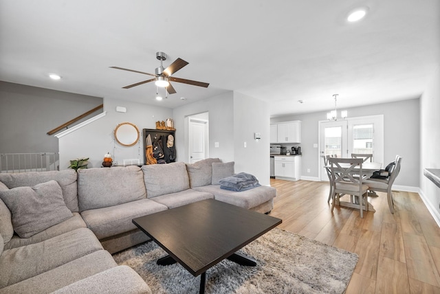 living room featuring light wood-style floors, ceiling fan with notable chandelier, baseboards, and recessed lighting