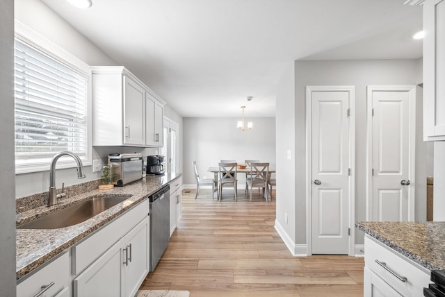 kitchen with stone counters, a sink, white cabinets, hanging light fixtures, and dishwasher