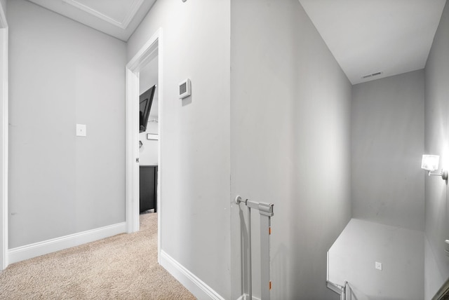 hallway with carpet floors, baseboards, and visible vents