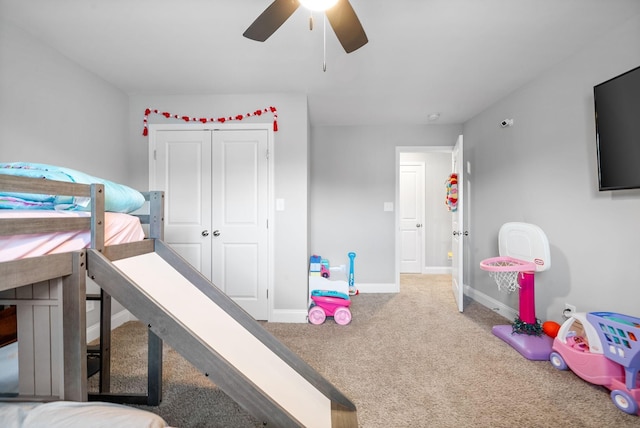 carpeted bedroom with a closet, baseboards, and a ceiling fan