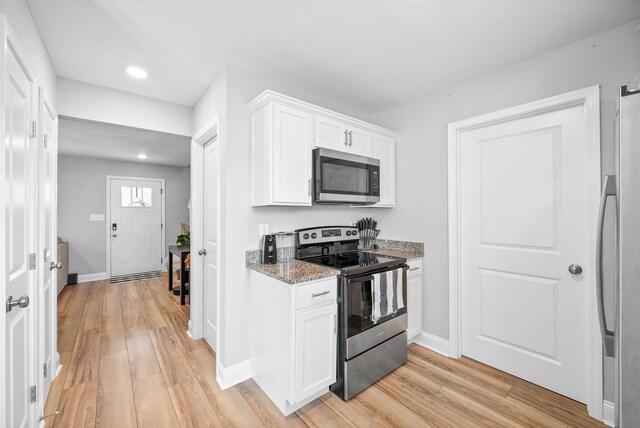 kitchen featuring appliances with stainless steel finishes, stone countertops, white cabinetry, and light wood-style floors