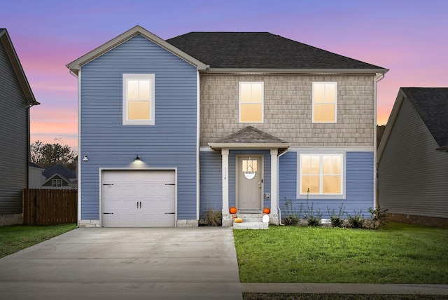 traditional-style home with entry steps, a garage, fence, concrete driveway, and a front yard