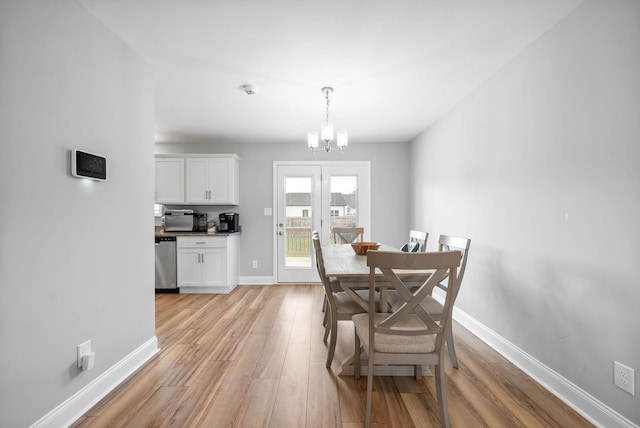 dining space with a chandelier, baseboards, and light wood finished floors