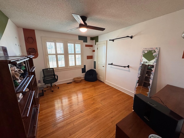 sitting room with a textured ceiling, visible vents, baseboards, a ceiling fan, and light wood finished floors