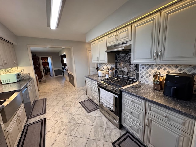 kitchen with under cabinet range hood, stainless steel appliances, marble finish floor, decorative backsplash, and dark stone countertops