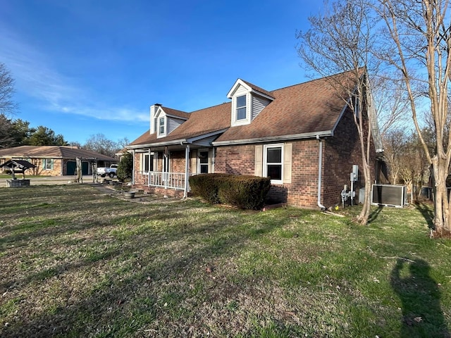 exterior space featuring brick siding, roof with shingles, a porch, central AC unit, and a front lawn