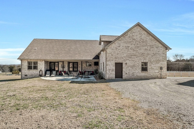 rear view of property with brick siding, a patio, fence, and a lawn