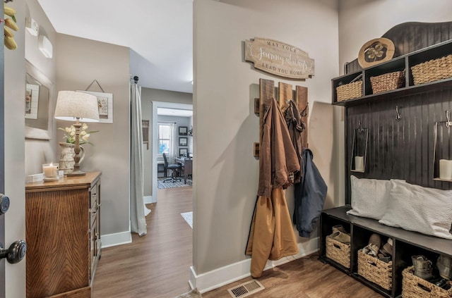 mudroom with baseboards, visible vents, and wood finished floors