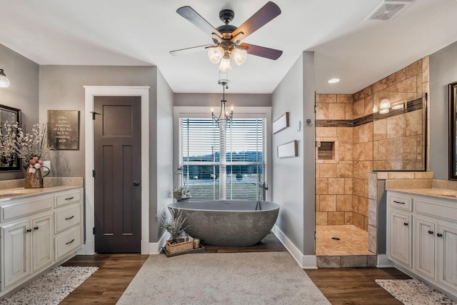 bathroom featuring wood finished floors, walk in shower, vanity, and visible vents