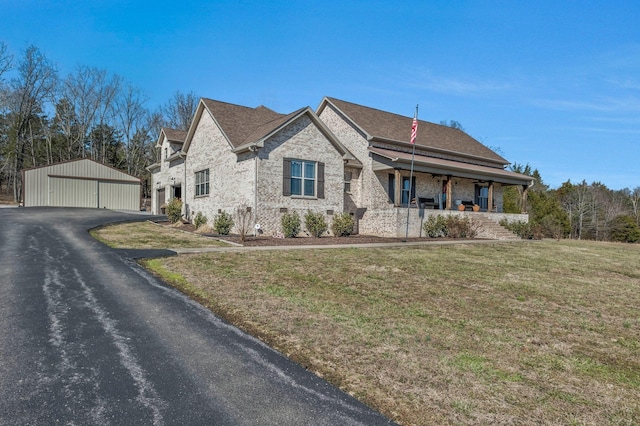 french country inspired facade with a porch, a front yard, roof with shingles, and an outdoor structure