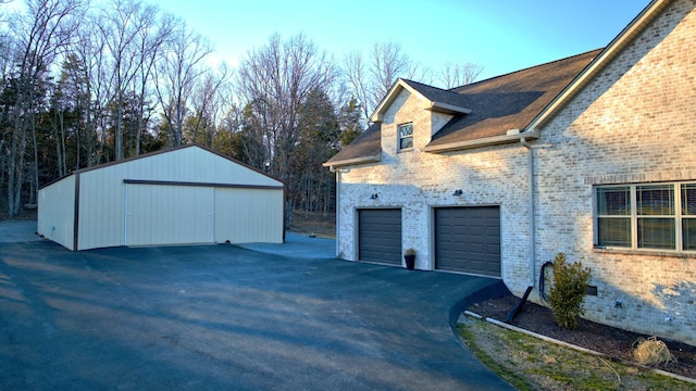 view of side of home featuring a garage, aphalt driveway, and brick siding