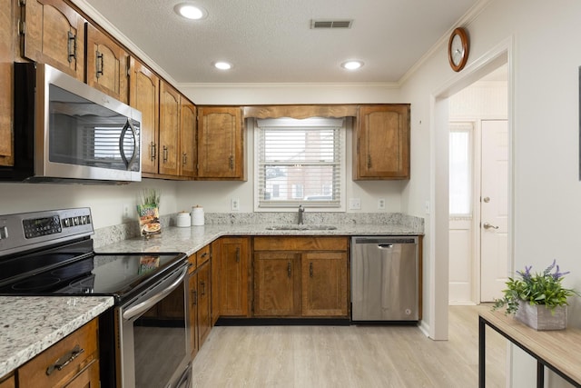 kitchen featuring appliances with stainless steel finishes, brown cabinetry, visible vents, and a sink