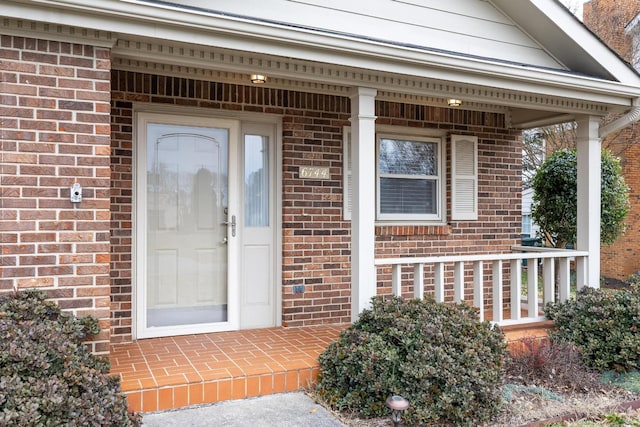 entrance to property with brick siding and a porch