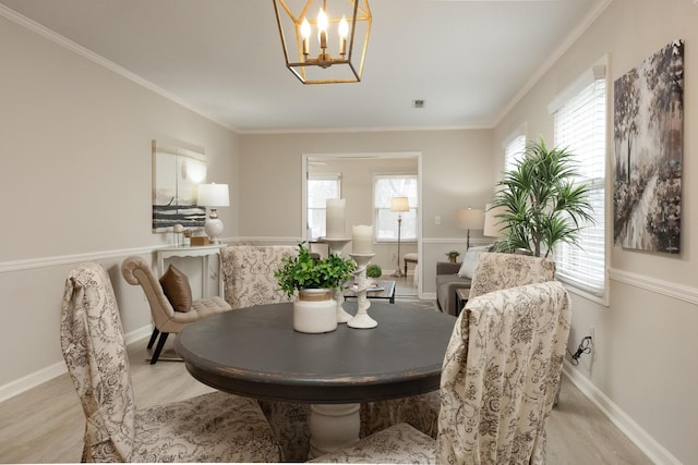 dining area featuring light wood-type flooring, crown molding, and baseboards