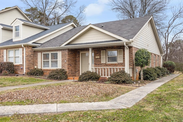 view of front of property featuring brick siding and roof with shingles