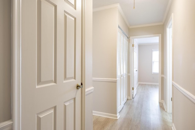 hall with ornamental molding, light wood-type flooring, and baseboards