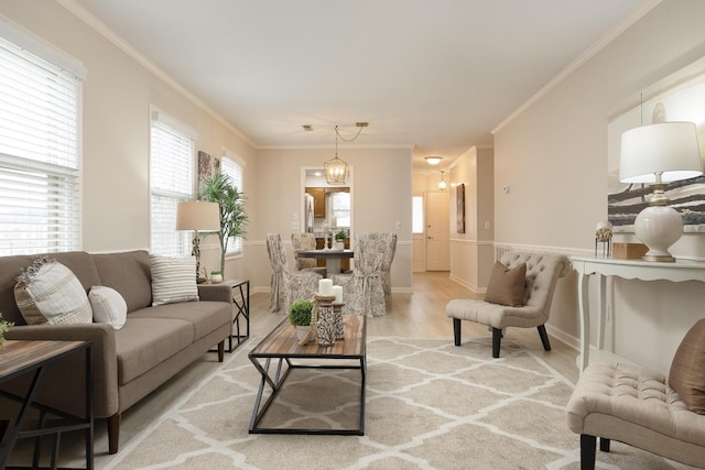 living room featuring a notable chandelier, crown molding, baseboards, and wood finished floors