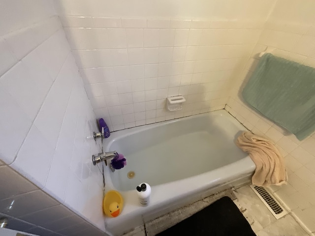 bathroom with a tub and visible vents