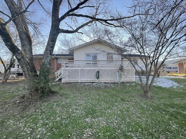 rear view of house with a deck, a lawn, and brick siding