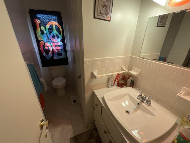 bathroom with tile patterned flooring, toilet, visible vents, vanity, and tile walls