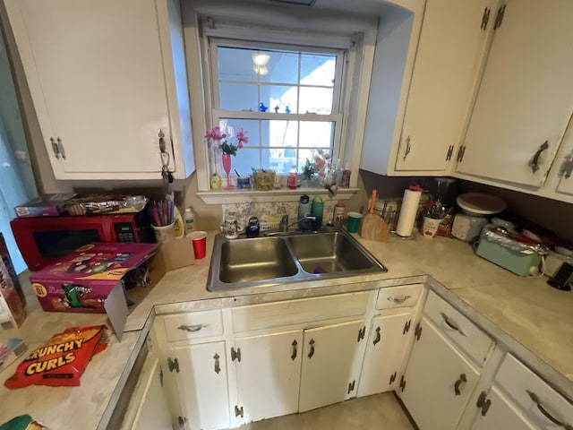 kitchen with white cabinets, light countertops, and a sink