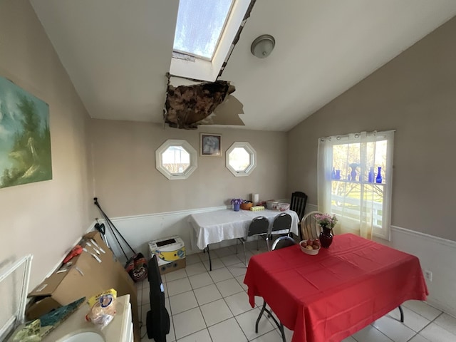 dining room featuring a wealth of natural light, vaulted ceiling with skylight, and light tile patterned floors