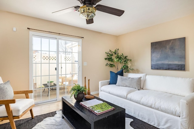 living area with ceiling fan, baseboards, and wood finished floors