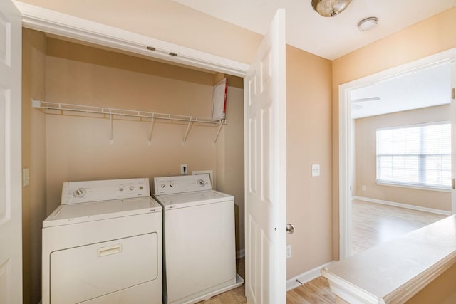 washroom with laundry area, baseboards, light wood finished floors, and washing machine and clothes dryer