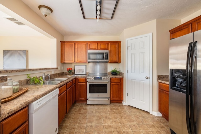 kitchen featuring visible vents, appliances with stainless steel finishes, brown cabinets, and a sink