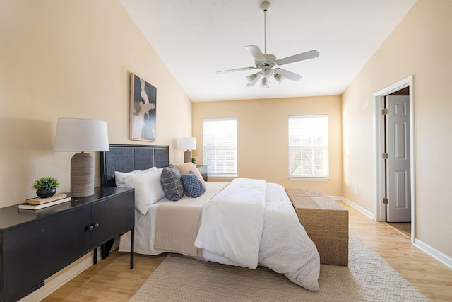 bedroom with vaulted ceiling, light wood-type flooring, a ceiling fan, and baseboards