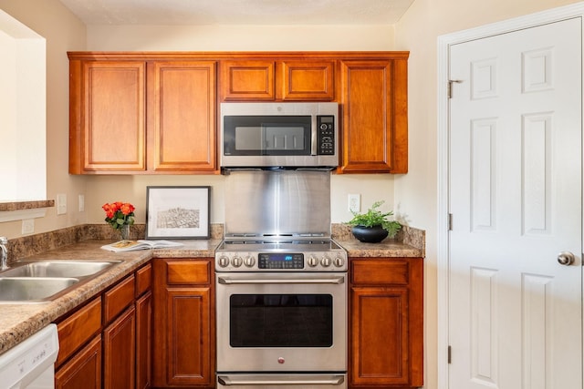 kitchen with light countertops, appliances with stainless steel finishes, a sink, and brown cabinets