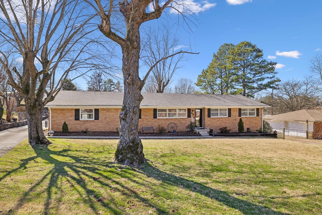 single story home featuring a garage, brick siding, a front yard, and fence