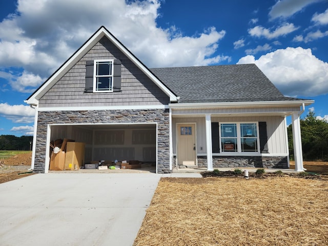 craftsman-style house featuring a garage, stone siding, roof with shingles, and driveway