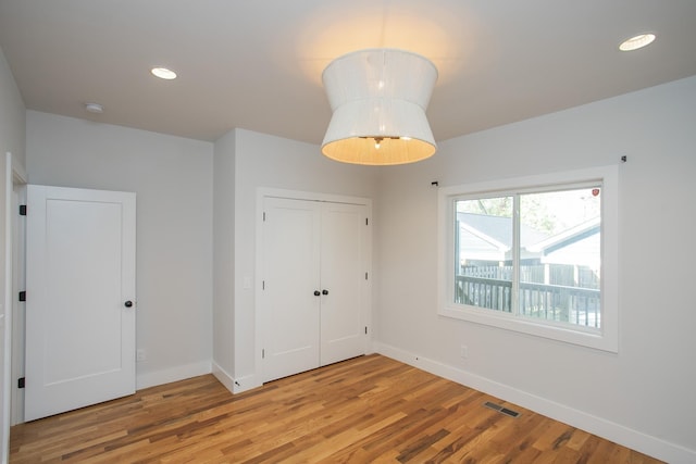 unfurnished bedroom with recessed lighting, a closet, visible vents, light wood-style floors, and baseboards