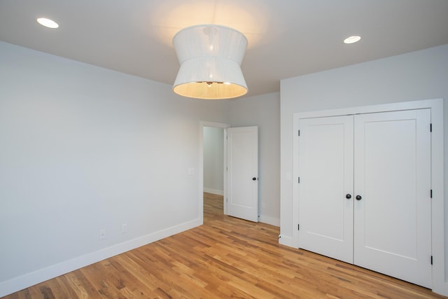 unfurnished bedroom with light wood-style flooring, baseboards, a closet, and recessed lighting