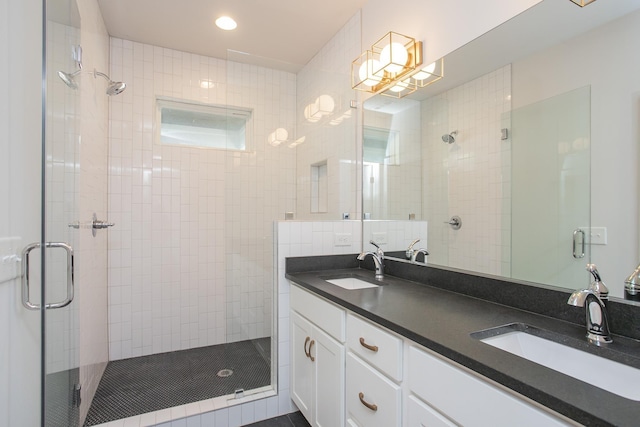 full bath with a stall shower, a sink, and double vanity