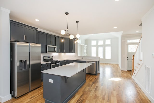 kitchen with a kitchen island, stainless steel appliances, light countertops, a kitchen bar, and pendant lighting