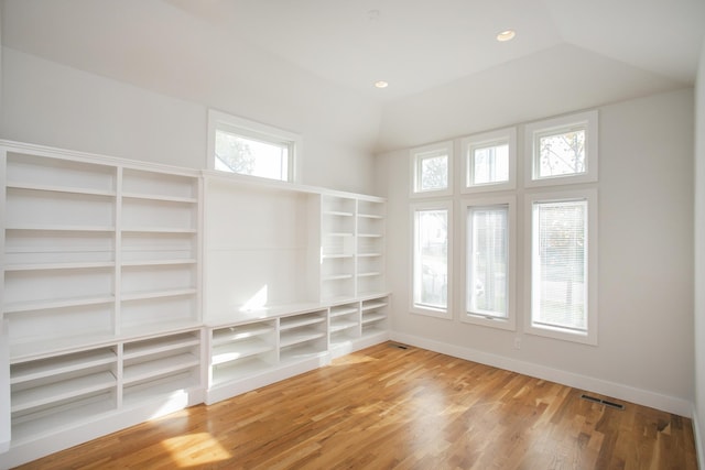 empty room with baseboards, visible vents, wood finished floors, vaulted ceiling, and recessed lighting