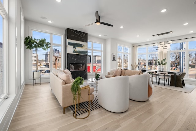 living area featuring light wood-type flooring, a high end fireplace, ceiling fan, and recessed lighting