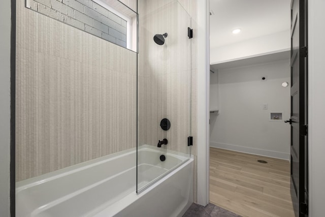 full bath featuring washtub / shower combination, a walk in closet, baseboards, and wood finished floors