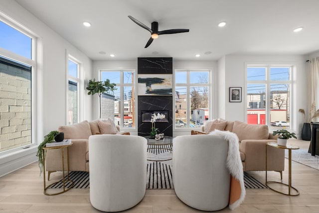 living area with ceiling fan, light wood finished floors, a premium fireplace, and recessed lighting