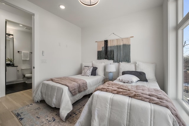 bedroom with recessed lighting, connected bathroom, and wood finished floors