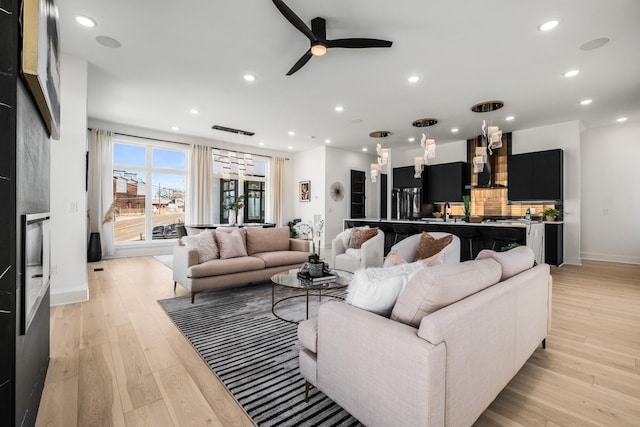 living area featuring light wood-style flooring, baseboards, ceiling fan, and recessed lighting