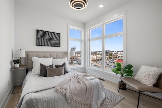 bedroom with light wood-style flooring, visible vents, and baseboards