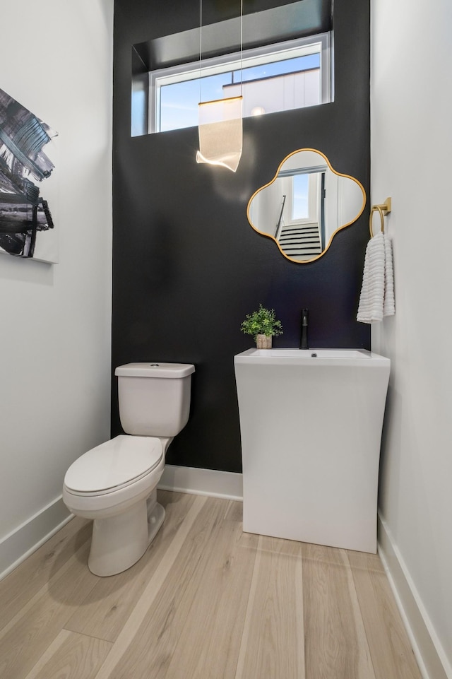 bathroom featuring toilet, baseboards, and wood finished floors