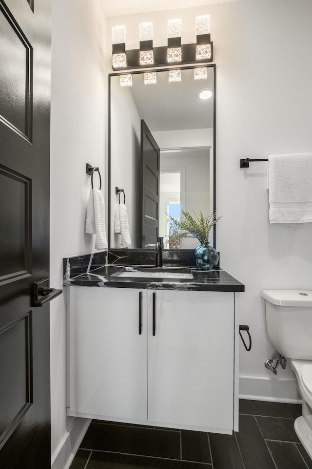 bathroom featuring tile patterned flooring, baseboards, vanity, and toilet