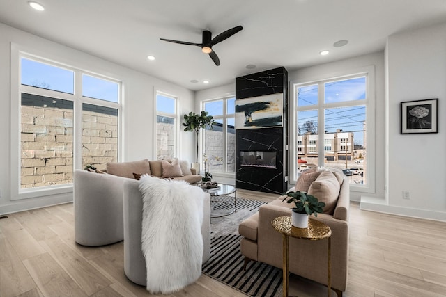 living room with light wood-style floors, a wealth of natural light, a fireplace, and baseboards