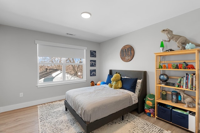 bedroom with light wood finished floors, visible vents, and baseboards