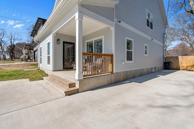 back of property with covered porch, fence, and concrete driveway