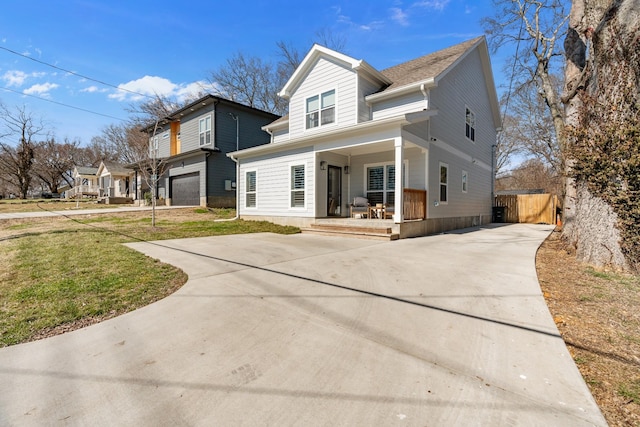 traditional-style house with a front yard, covered porch, driveway, and an attached garage